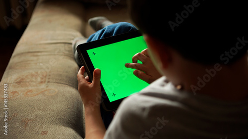 Child using a digital tablet PC with green screen