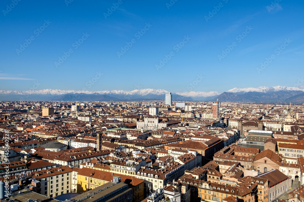 Aerial view of Torino, Italy from the top of the Mole Antonelliana towards the San Paolo Skyscraper (by Renzo Piano) with Alps in the background. Piazza Castello and the royal palace are also visible.