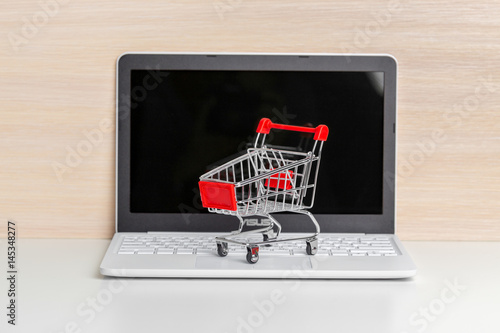 Shopping Cart On Laptop At Wooden Table
