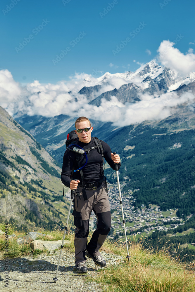 hiker at the top of a pass with backpack enjoy sunny day in Alps. Switzerland, Trek near Matterhorn mount.