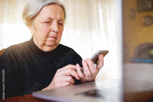 Grandmother looking at laptop using one hand typing searching internet.