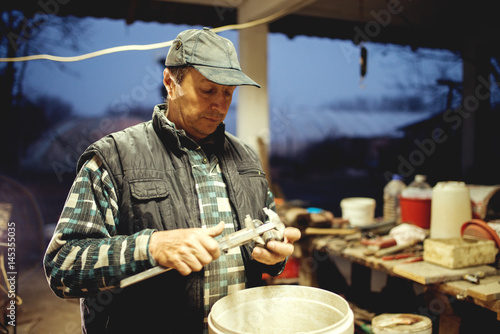 Middle aged man at workshop late night working hard.