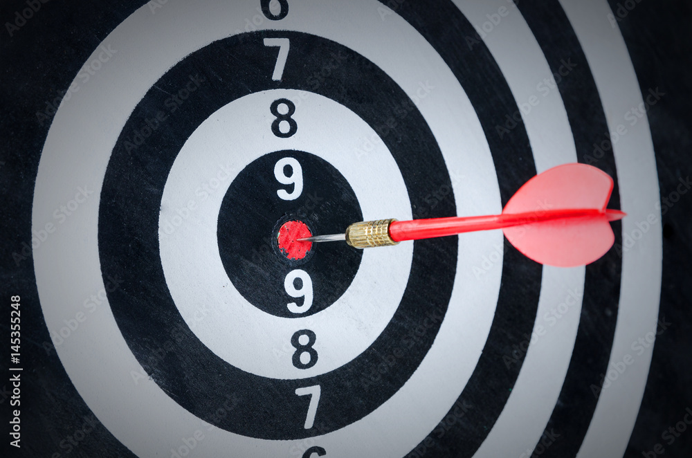 Close up shot red dart arrow on center of dartboard Close up shot red dart arrow on center of dartboard