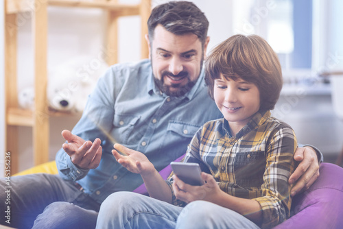 Canvas Print Father and son looking at cell phone together
