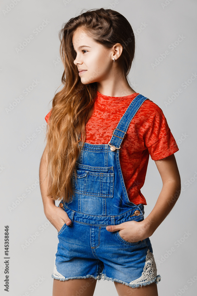 Girl teenager in denim overalls and a red t-shirt on a gray studio  background. Happy teenager looking away. Beautiful girl with thick hair.  Stock Photo | Adobe Stock