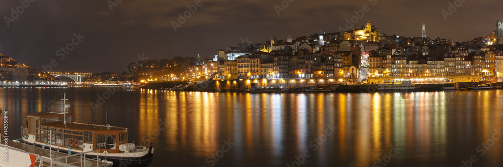 Panorama of Ribeira and Old town of Porto with mirror reflections in the Douro River at night, Portugal, Portugal.