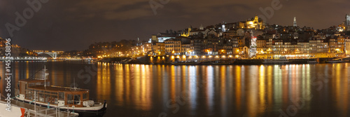 Panorama of Ribeira and Old town of Porto with mirror reflections in the Douro River at night, Portugal, Portugal. © Kavalenkava