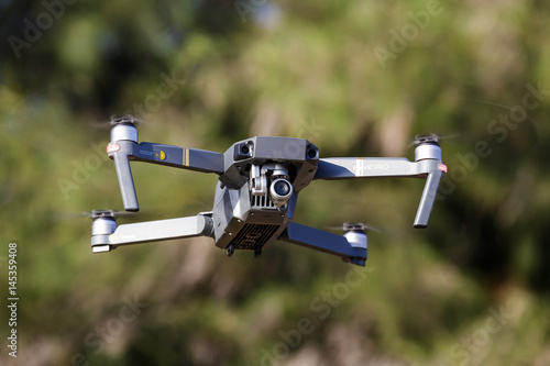 Unmanned aerial vehical with video camera hovers in the air. This is DJI Mavic Pro model. photo