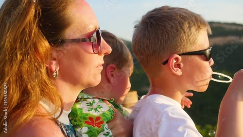 Boy making soap bubbles with mom and brother. Panoramic view photo