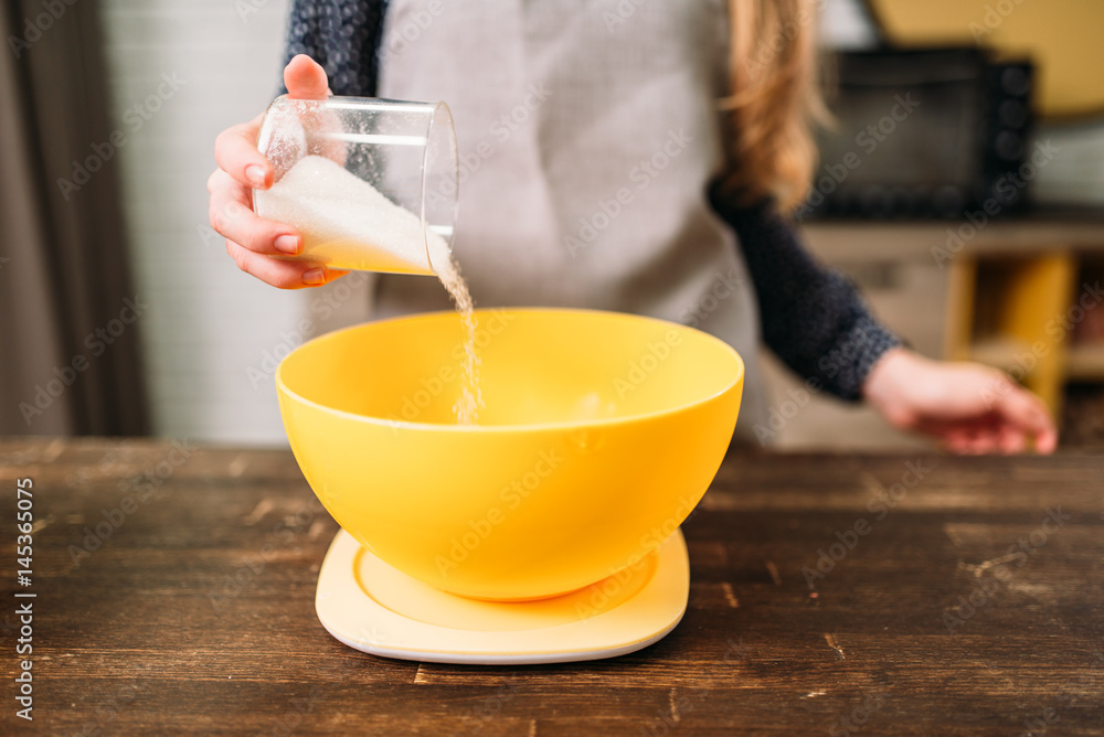 Female hands adds sugar into a bowl with dough Female hands adds sugar into a bowl with dough