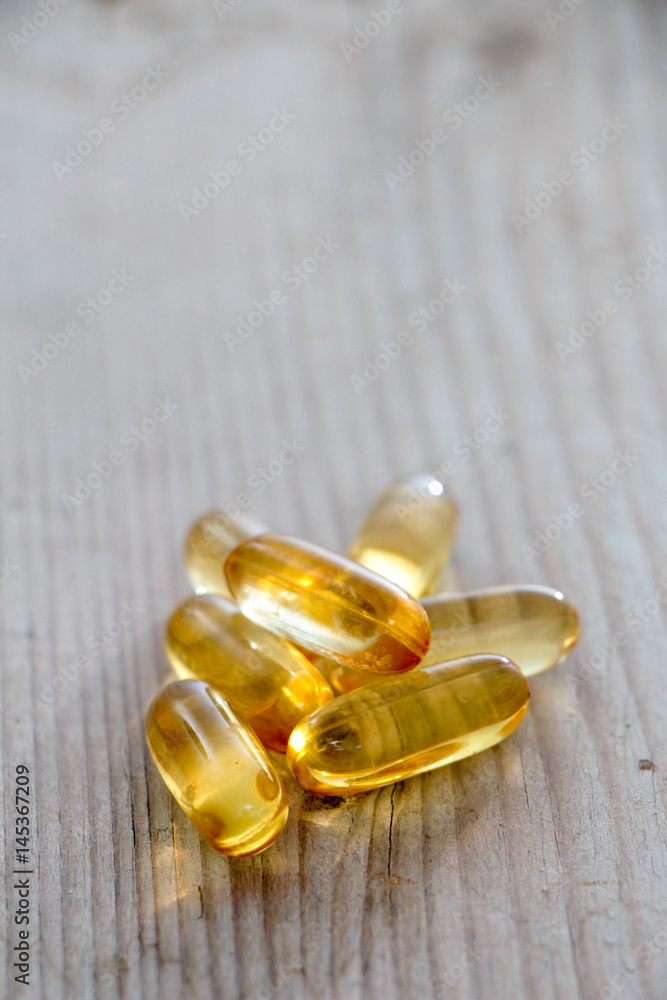 Pile of capsules Omega 3 on wood background. Close up, Pile of capsules Omega 3 on wood background. Close up,