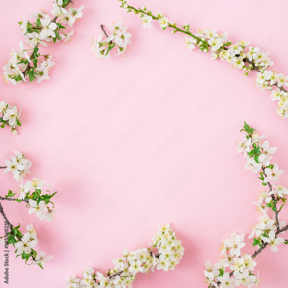 Spring time background. Floral frame of spring white flowers on pink background. Flat lay, top view.