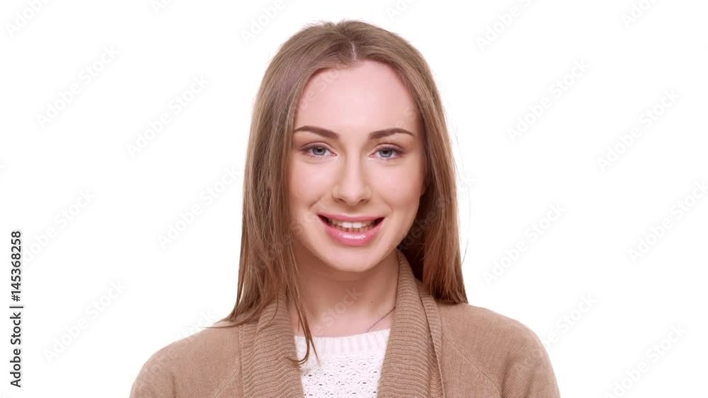 Attractive young Caucasian female with light brown hair looking at camera laughing standing on white background in slowmotion Attractive young Caucasian female with light brown hair looking at camera laughing standing on white background in slowmotion