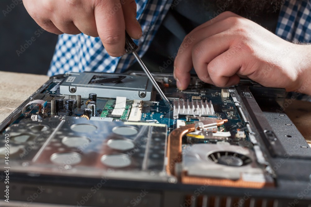 Engineer hands repairs laptop with screwdriver Engineer hands repairs laptop with screwdriver