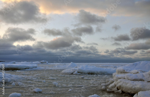 Frozen seascape with colorful clouds at sunset.