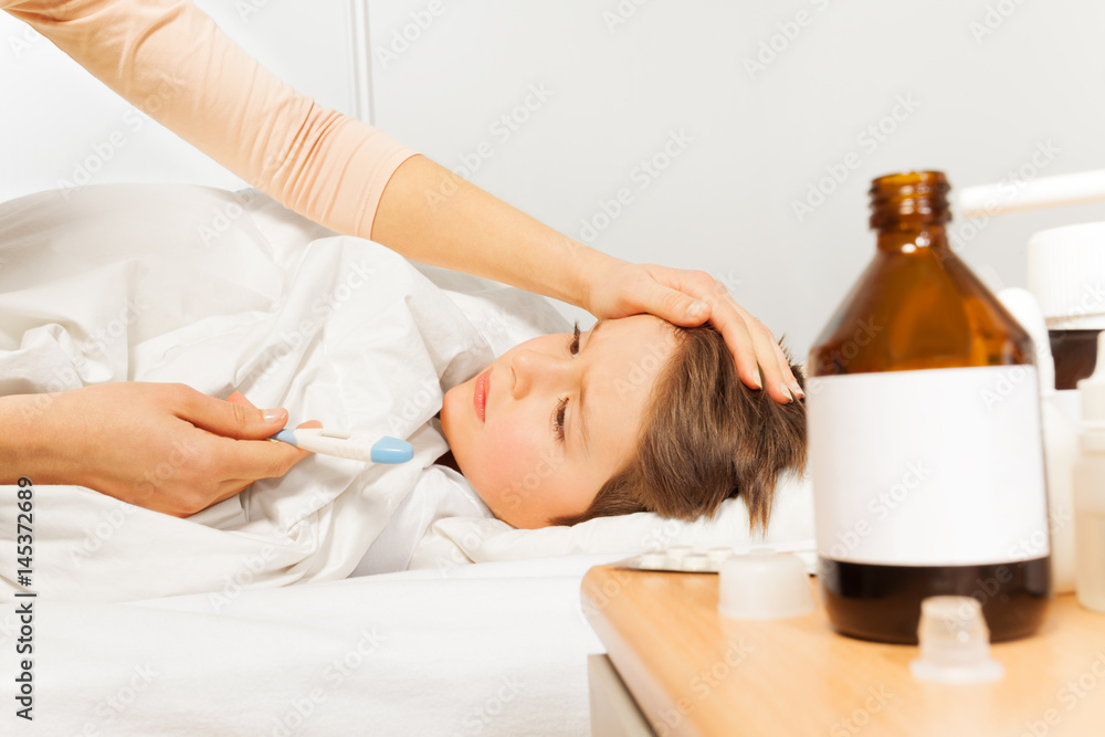 Woman caressing her son and checking temperature Woman caressing her son and checking temperature