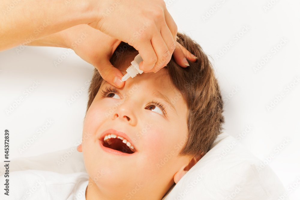 Fototapeta premium Woman helping kid boy to instill eye drops