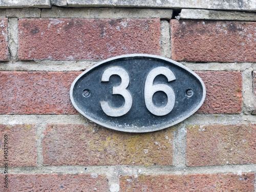 a number plate on a brick wall with 36 on it