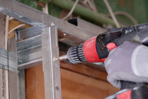 Man in gloves drilling with hand drill