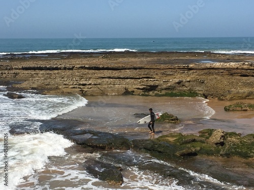 a surfer walks into the Atlantic ocean in Morocco