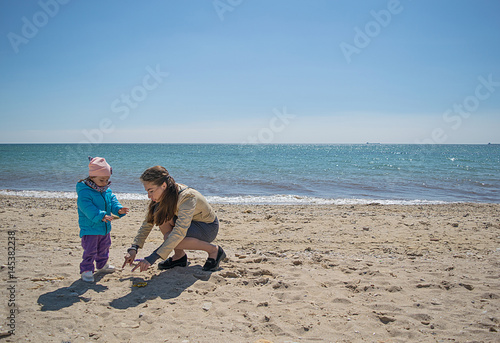 Mom and daughter playing on the beach in the spring