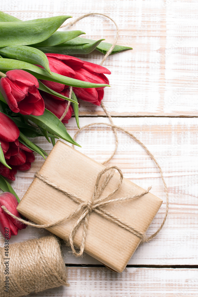Gift box and tulips bouquet on white wooden background - retro style Gift box and tulips bouquet on white wooden background - retro style