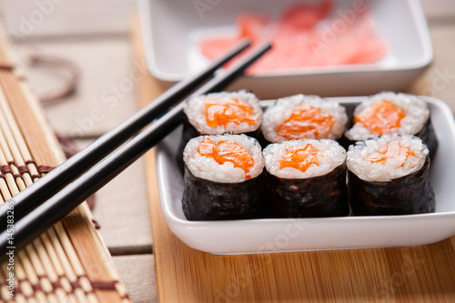 Sushi rolls with salmon, ginger and chopsticks 