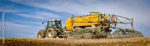 Canvastavla Tractor with yellow vacuum manure spreader on a field, wide format