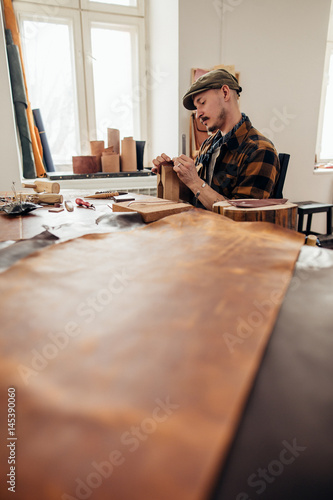 Working process of the leather wallet in the leather workshop. man holding crafting tool and iron ruler