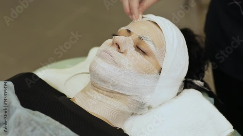 A bandage mask using gauze fabric. Application of cream on the laid gauze cloth on the face. photo