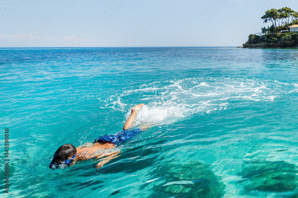 Boy snorkeling in the sea by the bank.