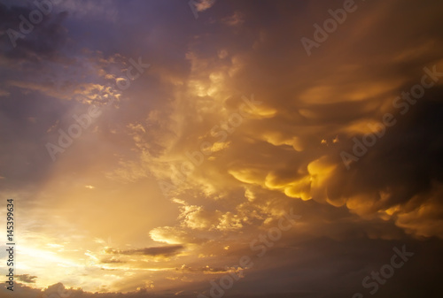 Beautiful dark fluffy cloudy sky with sun rays. Sunset light. © es0lex