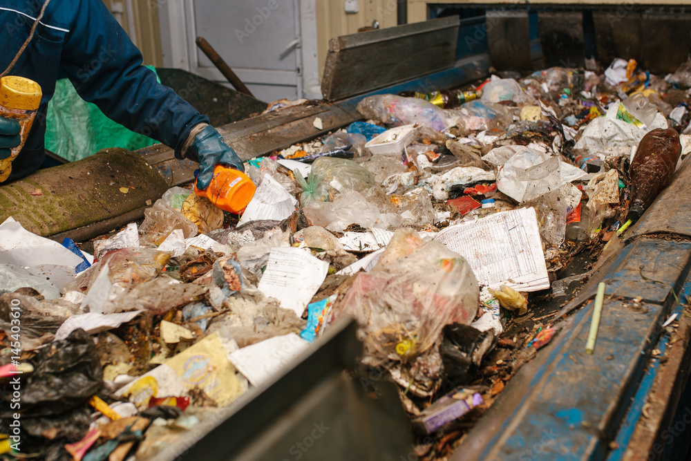 The worker sorts the waste received by a modern plant for sorting and recycling waste. Waste processing plant. Technological process. Recycling and storage of waste for further disposal. The worker sorts the waste received by a modern plant for sorting and recycling waste. Waste processing plant. Technological process. Recycling and storage of waste for further disposal.