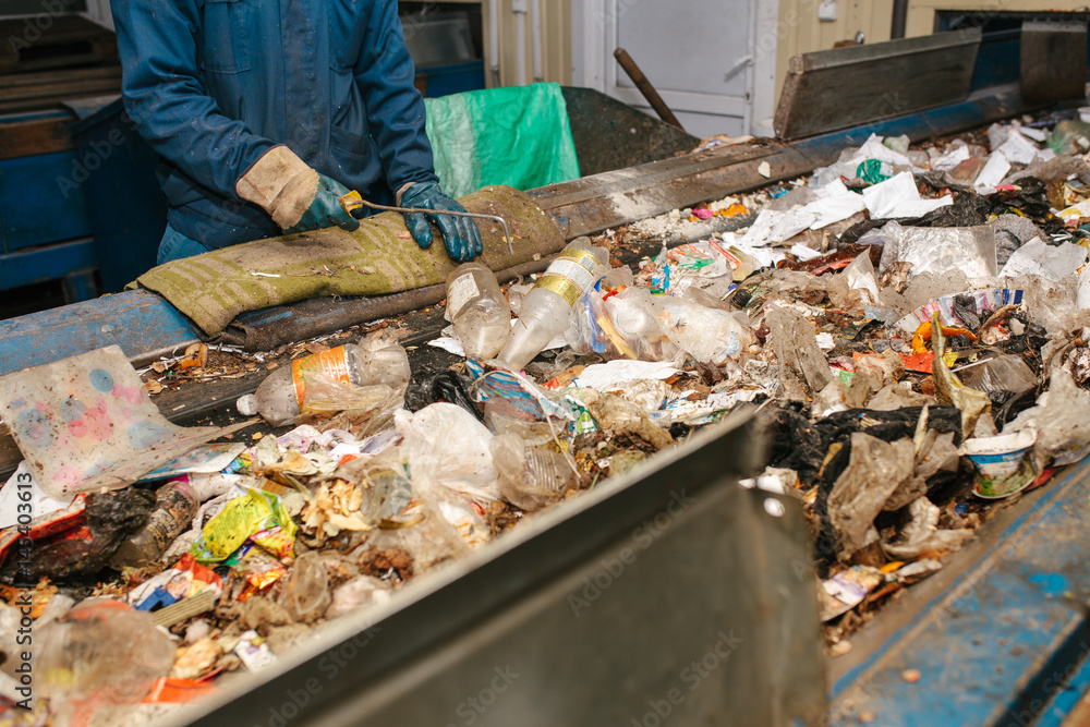 The worker sorts the waste received by a modern plant for sorting and recycling waste. Waste processing plant. Technological process. Recycling and storage of waste for further disposal. The worker sorts the waste received by a modern plant for sorting and recycling waste. Waste processing plant. Technological process. Recycling and storage of waste for further disposal.