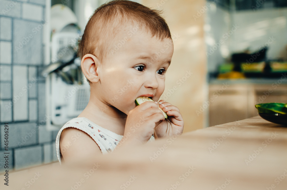 Little boy eating a fresh cucumber