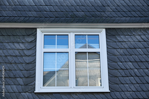 White colonial style window in a black facade covered in black layered slate, typical Winterberg building style