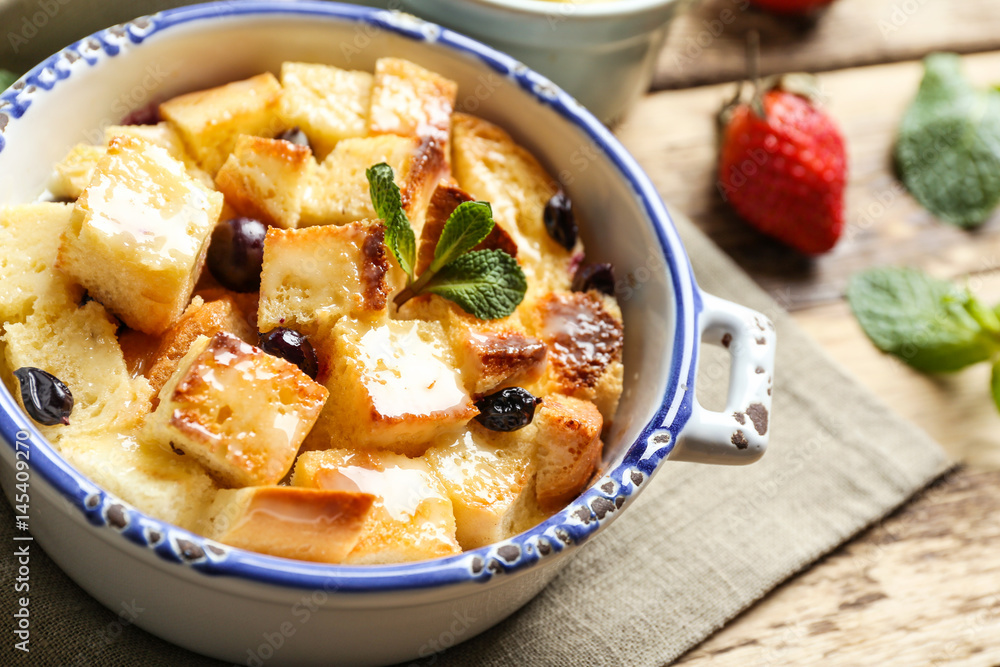 Delicious bread pudding with berries in bowl on napkin Delicious bread pudding with berries in bowl on napkin