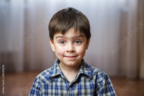 Charming boy in blue checkered shirt cute smiling looking straight at camera