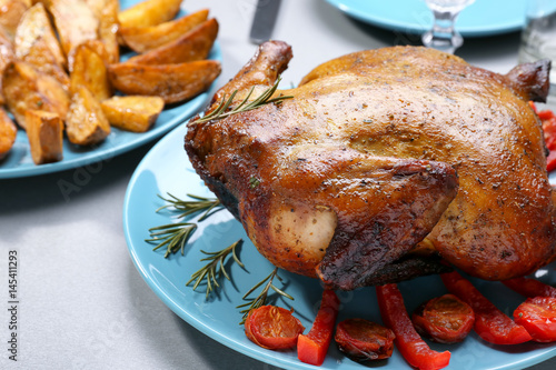 Plate with roasted beer can chicken on gray table