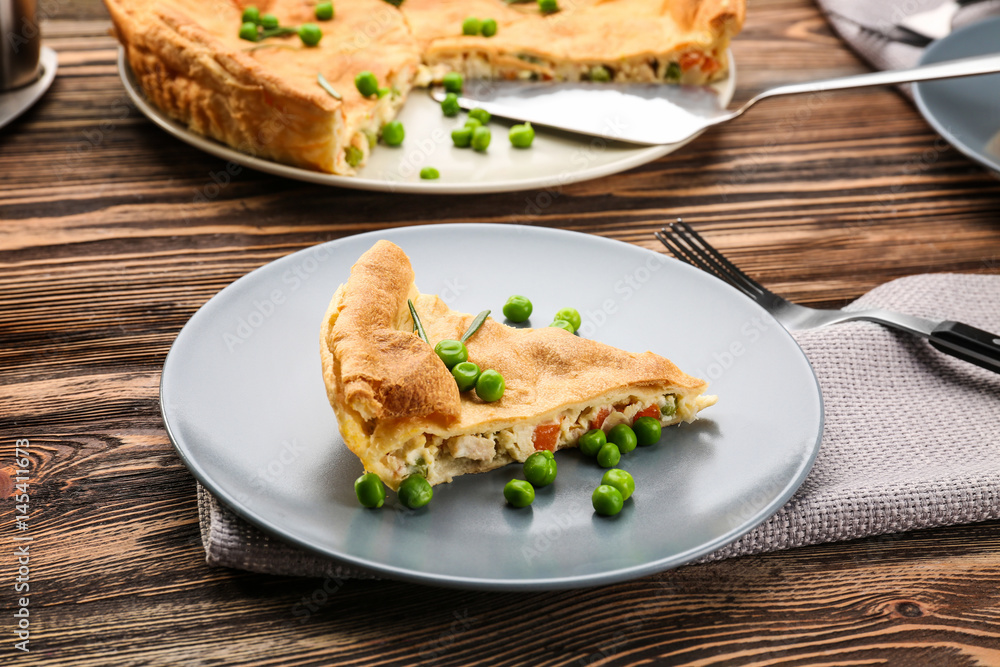Piece of tasty chicken pot pie with green peas on plate