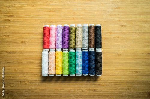 various color spindle thread arranged on the wood texture background which can be used a graphic resources.