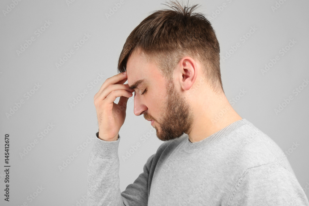 Young man suffering from headache on light background Young man suffering from headache on light background
