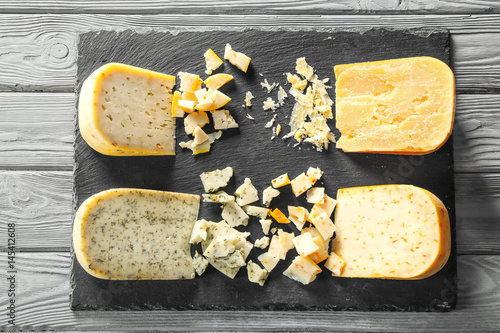 Slate plate with four sorts of cheese on wooden background photo