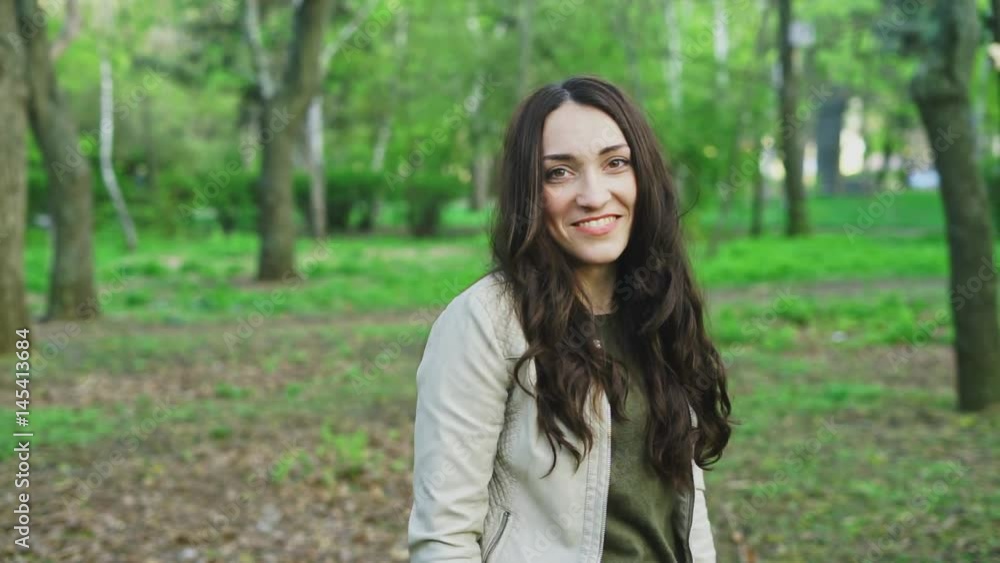 Brunette girl is turning around and smiling. She looks happy to meet a person. Slow motion shoot of pure emotions. Brunette girl is turning around and smiling. She looks happy to meet a person. Slow motion shoot of pure emotions.