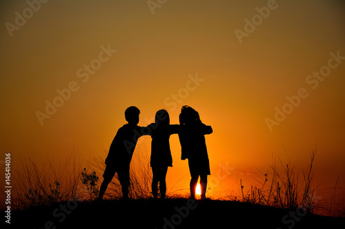 Silhouette  friendship of three on sunset mountain. © surasak
