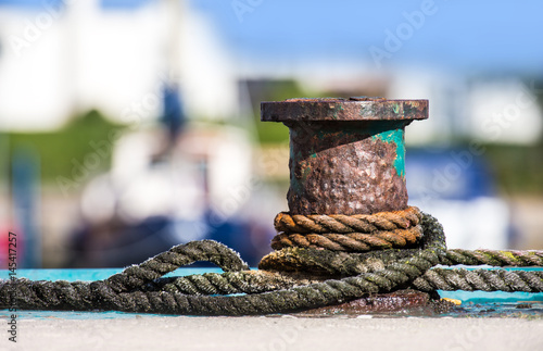 An old, rusty bollard in a harbor by the sea