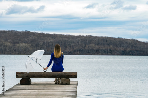 Slika na platnu A lonely girl is sad with an umbrella sitting on a bench in the rain on a scribb