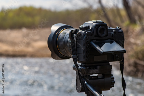 Photographic camera of a traveler in the wild on the coast of a mountain river