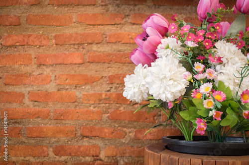 Artificial flowers and brick wall