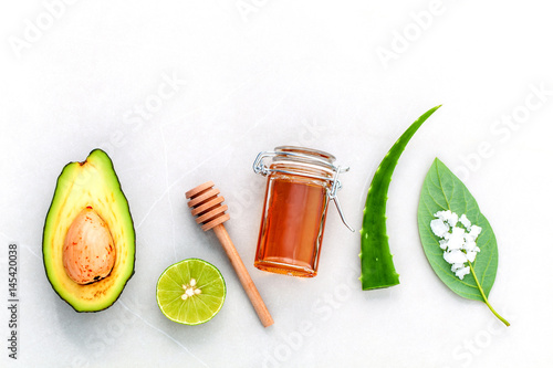 Homemade skin care and body scrub with natural ingredients fresh  avocado , leaves ,sea salt , lime and honey on marble background  with flat lay.